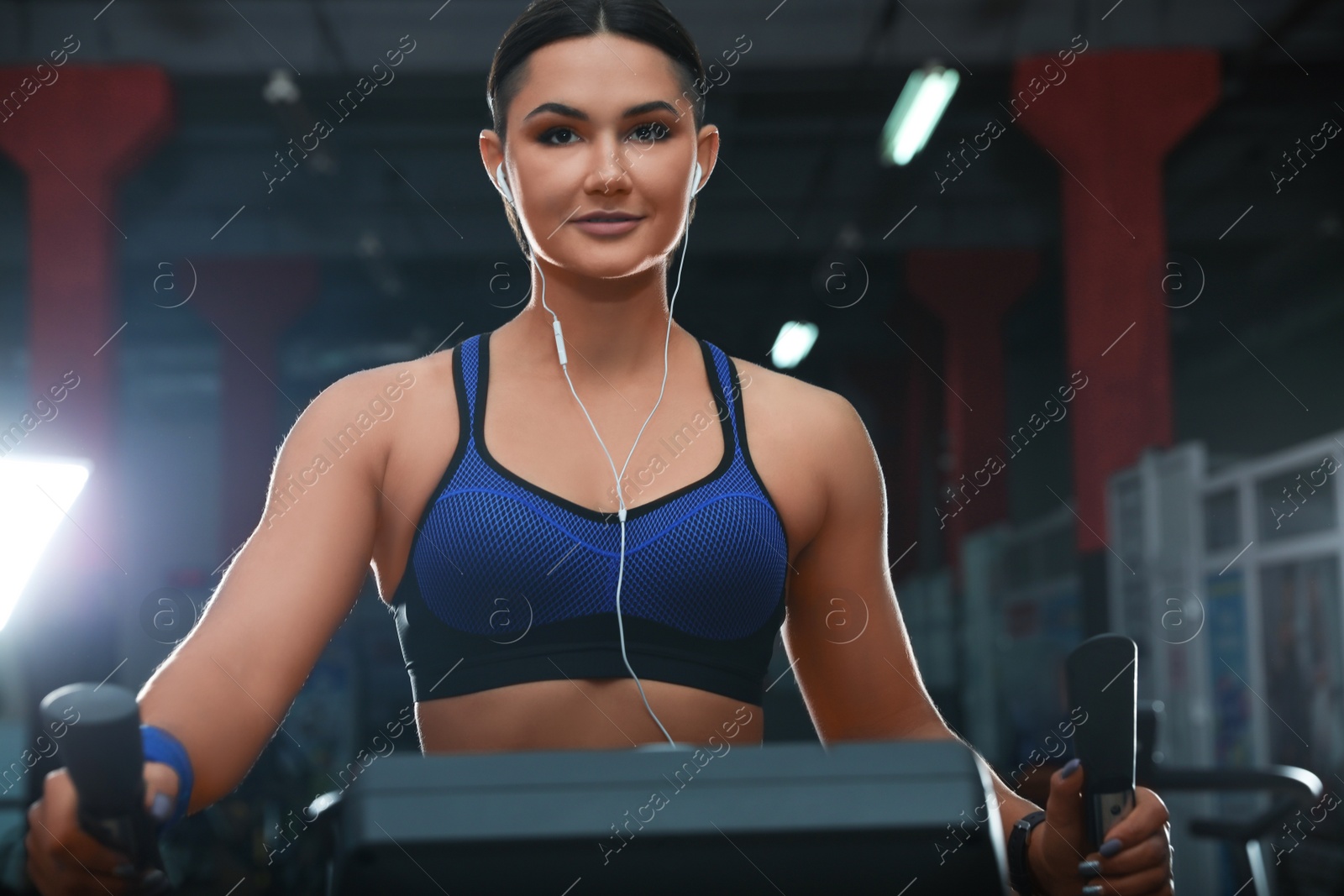 Photo of Young woman working out on elliptical trainer in modern gym