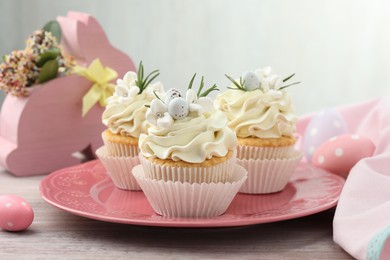 Photo of Tasty Easter cupcakes with vanilla cream on wooden table