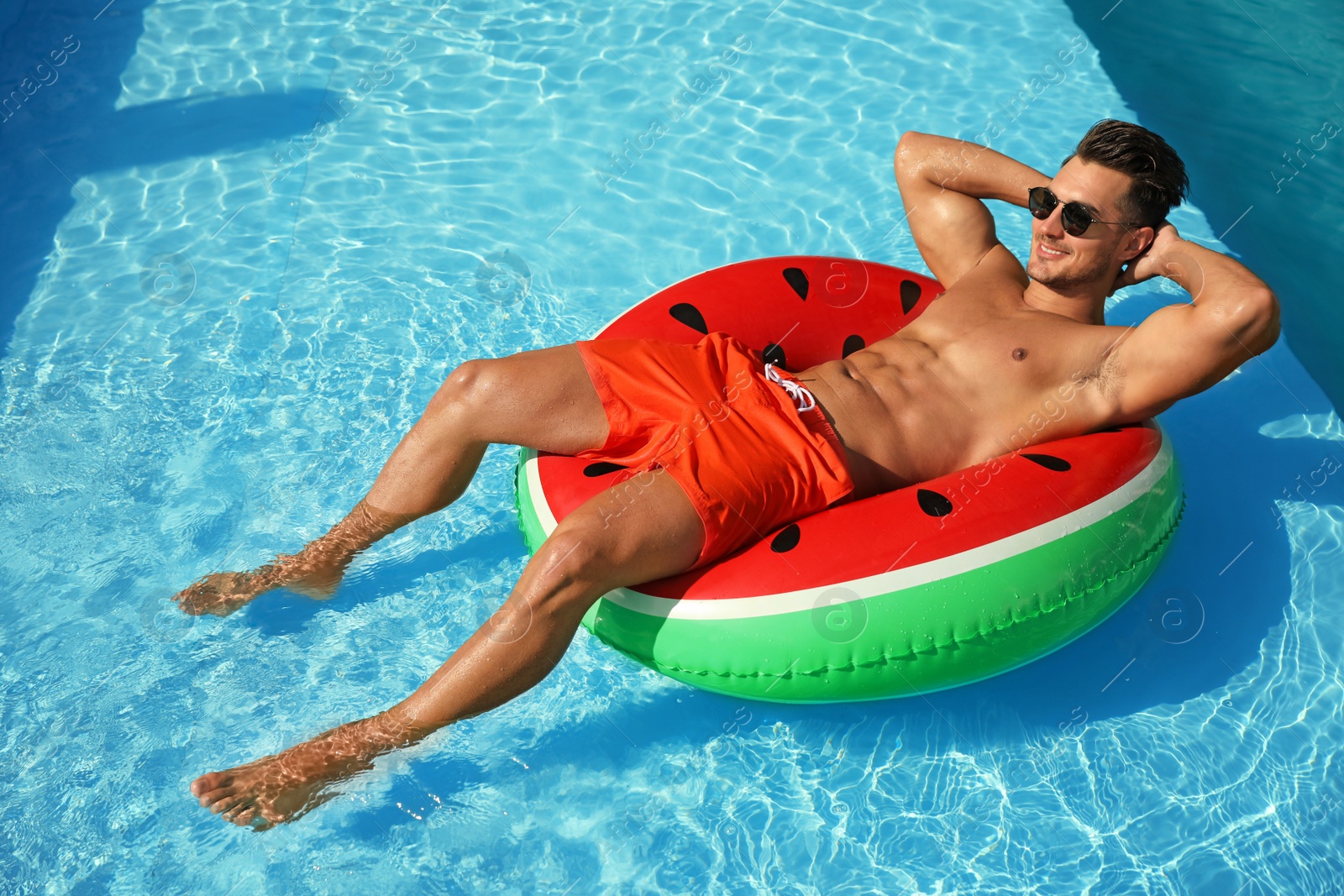 Photo of Young man with inflatable ring in pool on sunny day