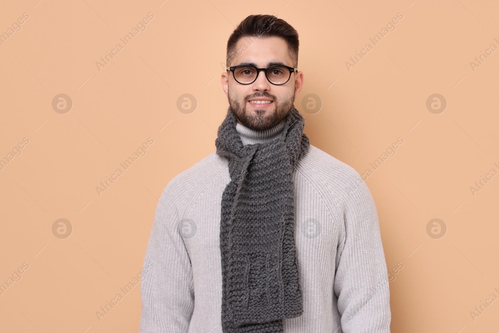 Photo of Smiling man in knitted scarf on beige background