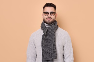 Photo of Smiling man in knitted scarf on beige background