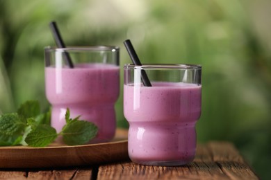 Photo of Delicious blackberry smoothie in glasses on wooden table