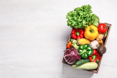 Photo of Crate with different fresh vegetables on light background, top view. Space for text