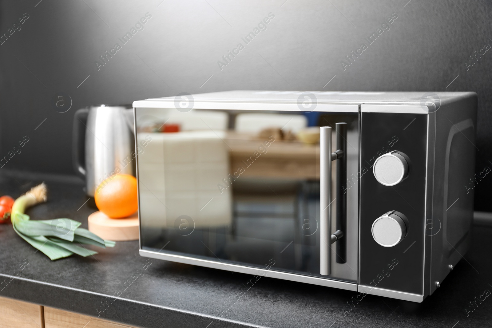 Photo of Modern microwave oven and ingredients on table in kitchen