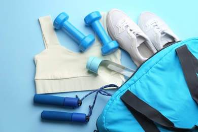 Composition with gym bag and sports items on light blue background, above view