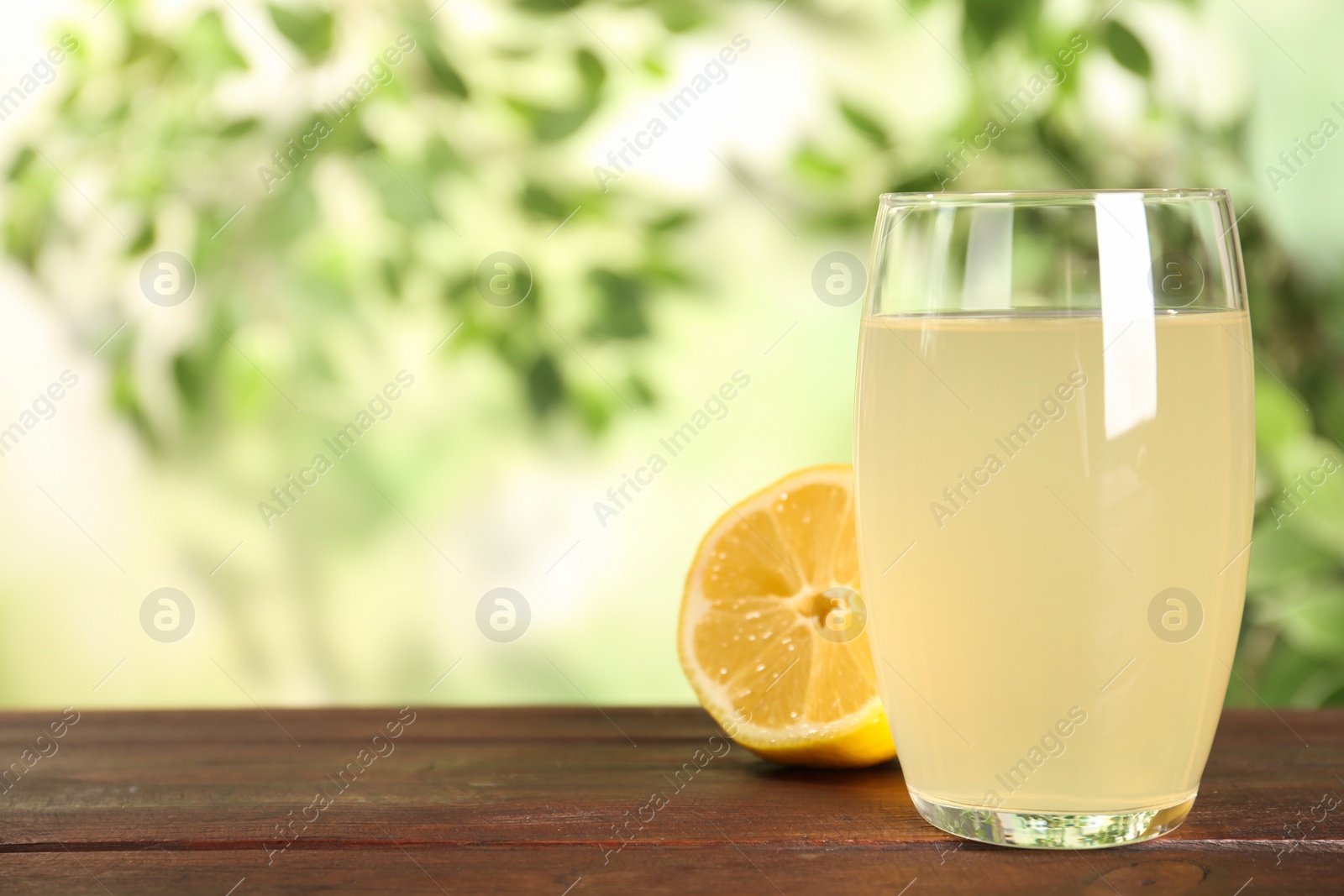 Photo of Delicious refreshing drink and lemon on wooden table, closeup. Space for text