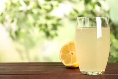 Photo of Delicious refreshing drink and lemon on wooden table, closeup. Space for text