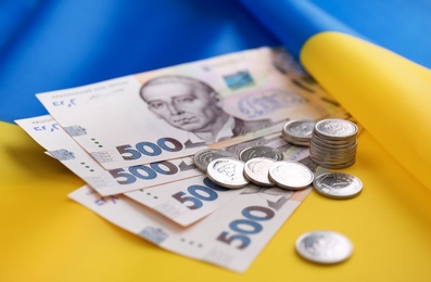 Photo of Ukrainian money on national flag, closeup view