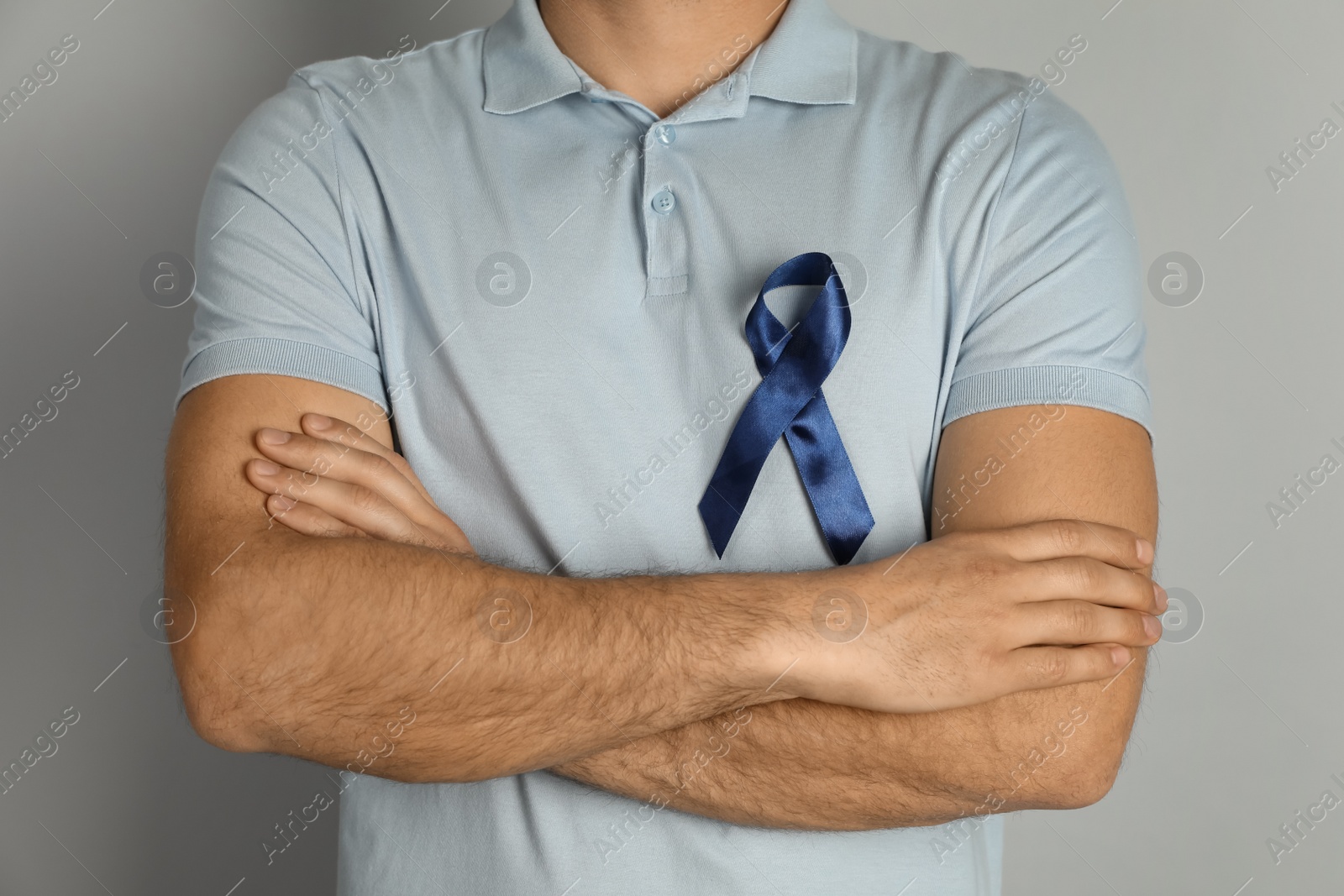 Photo of Man with blue ribbon on grey background, closeup. Urology cancer awareness