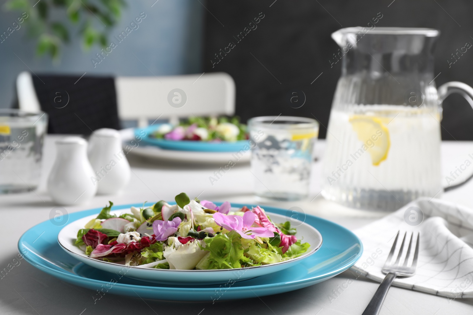 Photo of Fresh spring salad with flowers served on white table