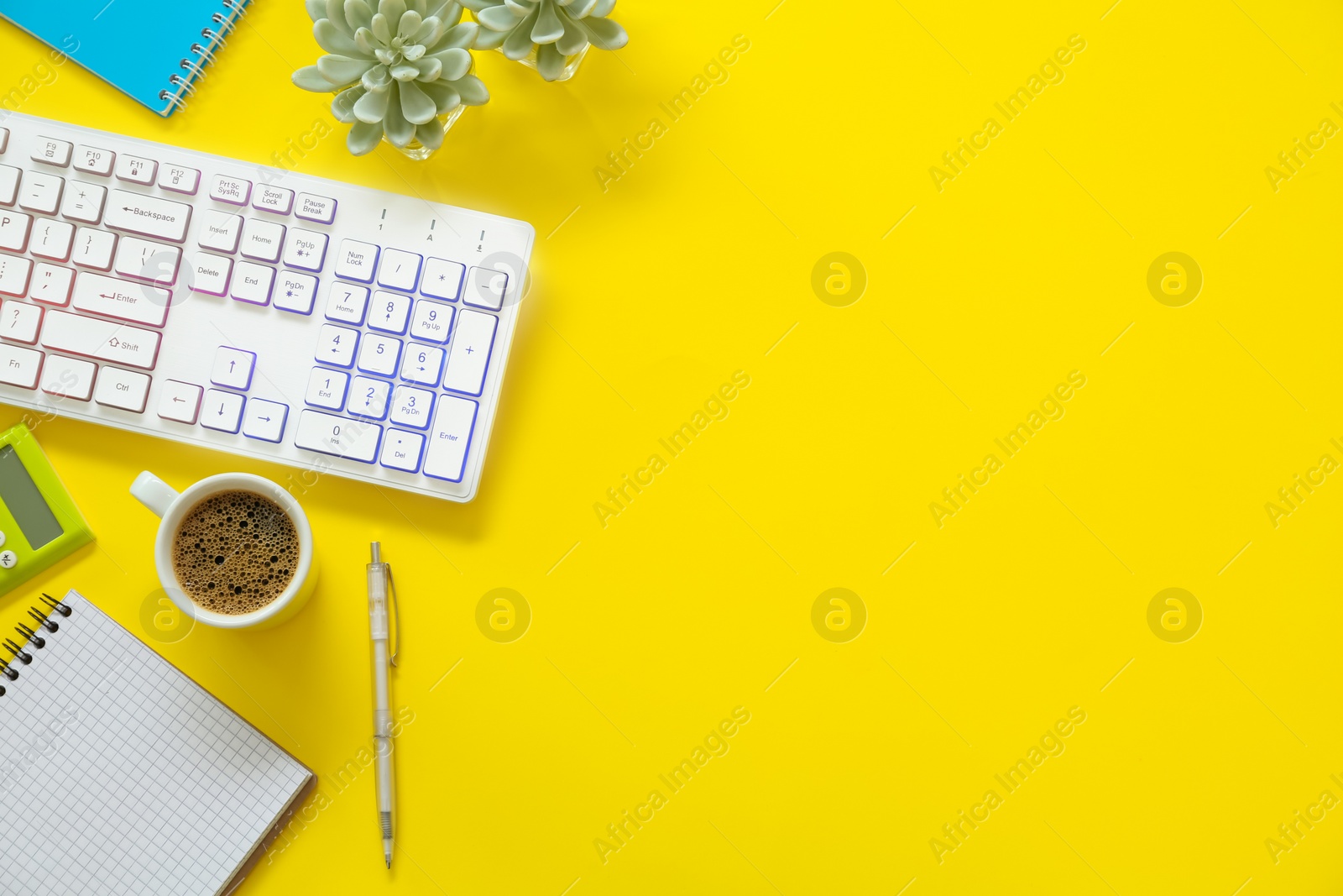 Photo of Modern keyboard with RGB lighting and stationery on yellow background, flat lay. Space for text