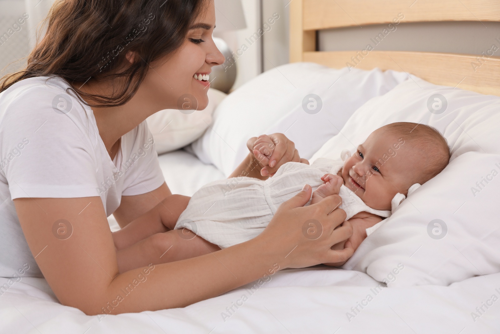 Photo of Happy young mother with her cute baby on bed at home