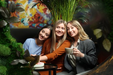 Photo of Young women flirting with guys at next table in cafe