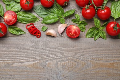 Flat lay composition with fresh basil leaves and vegetables on wooden table. Space for text