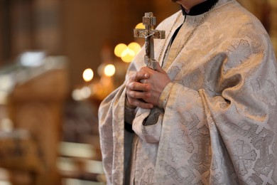Photo of Priest holding cross in church during baptism ceremony, closeup