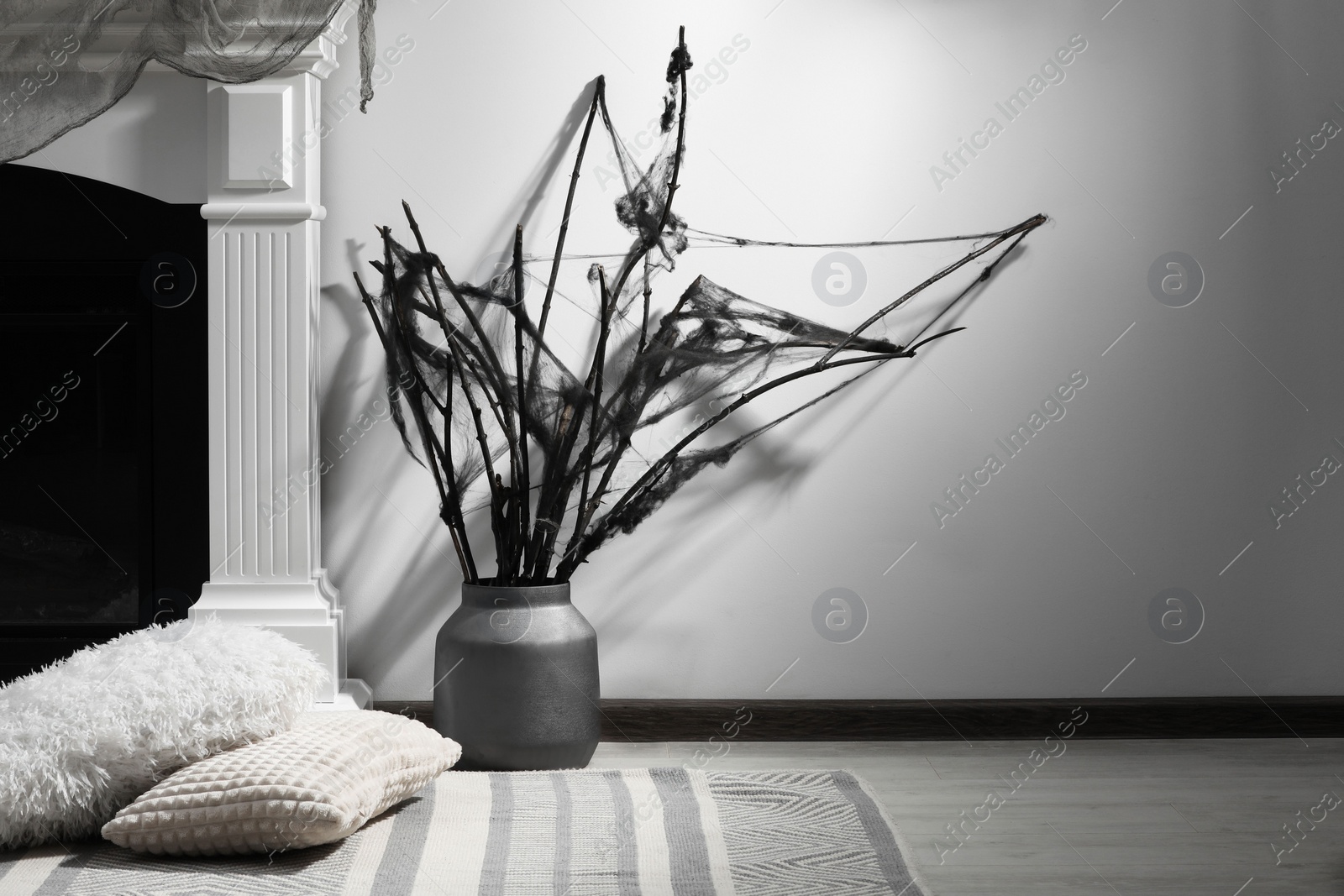 Photo of Black branches with cobweb in vase near fireplace indoors, space for text