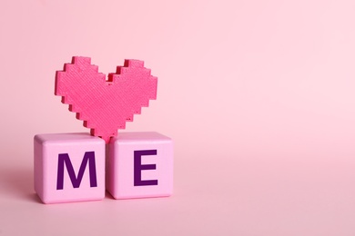 Photo of Phrase Love Me made with cubes and heart on pink background