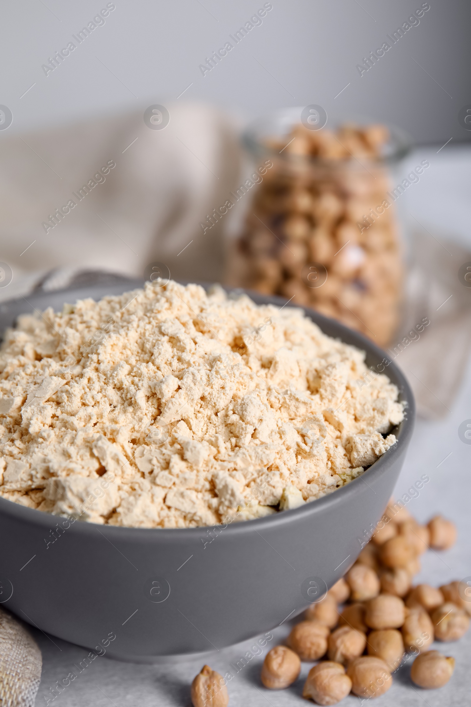 Photo of Chickpea flour in bowl and seeds on table, closeup