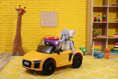 Child's electric car with toy elephant in playroom