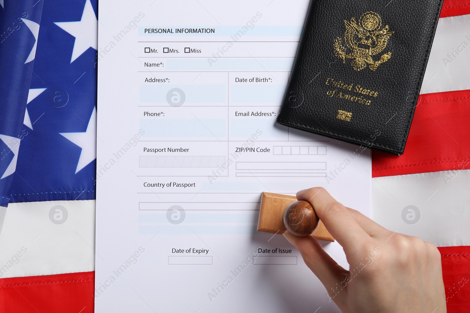 Photo of Immigration to USA. Woman stamping visa application form on flag, top view