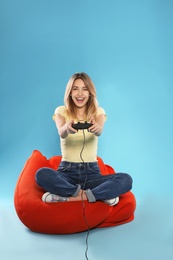 Photo of Emotional young woman playing video games with controller on color background. Space for text