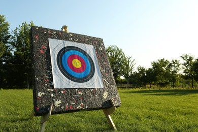 Photo of Tripod with archery target on green grass in park. Space for text