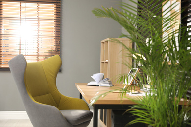 Photo of Comfortable workplace with wooden table and armchair