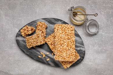 Photo of Board with puffed rice bars (kozinaki) on grey table, flat lay