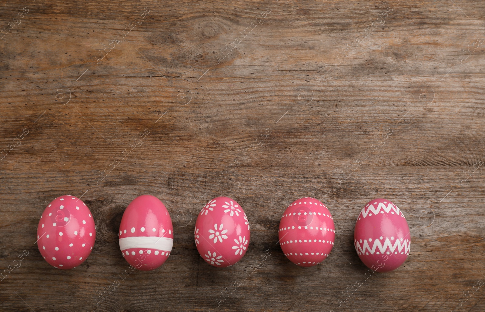 Photo of Decorated Easter eggs and space for text on wooden background, top view