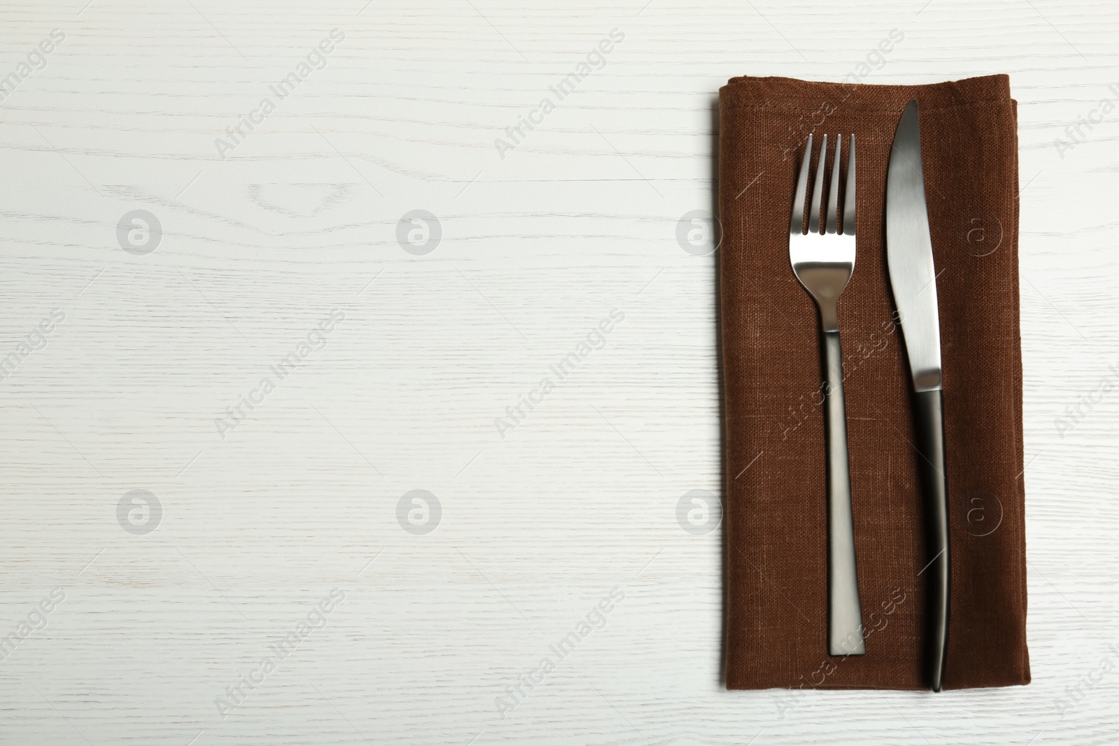 Photo of Cutlery and napkin on light wooden background, top view. Table setting