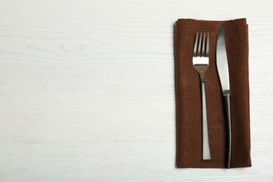 Cutlery and napkin on light wooden background, top view. Table setting