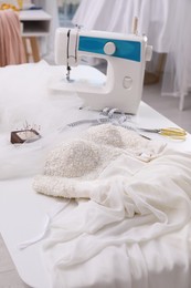 Beautiful wedding dress with embroidered bustline on table in dressmaking workshop