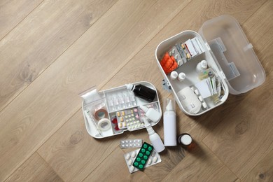 Photo of First aid kit and medicaments on floor indoors, flat lay. Space for text