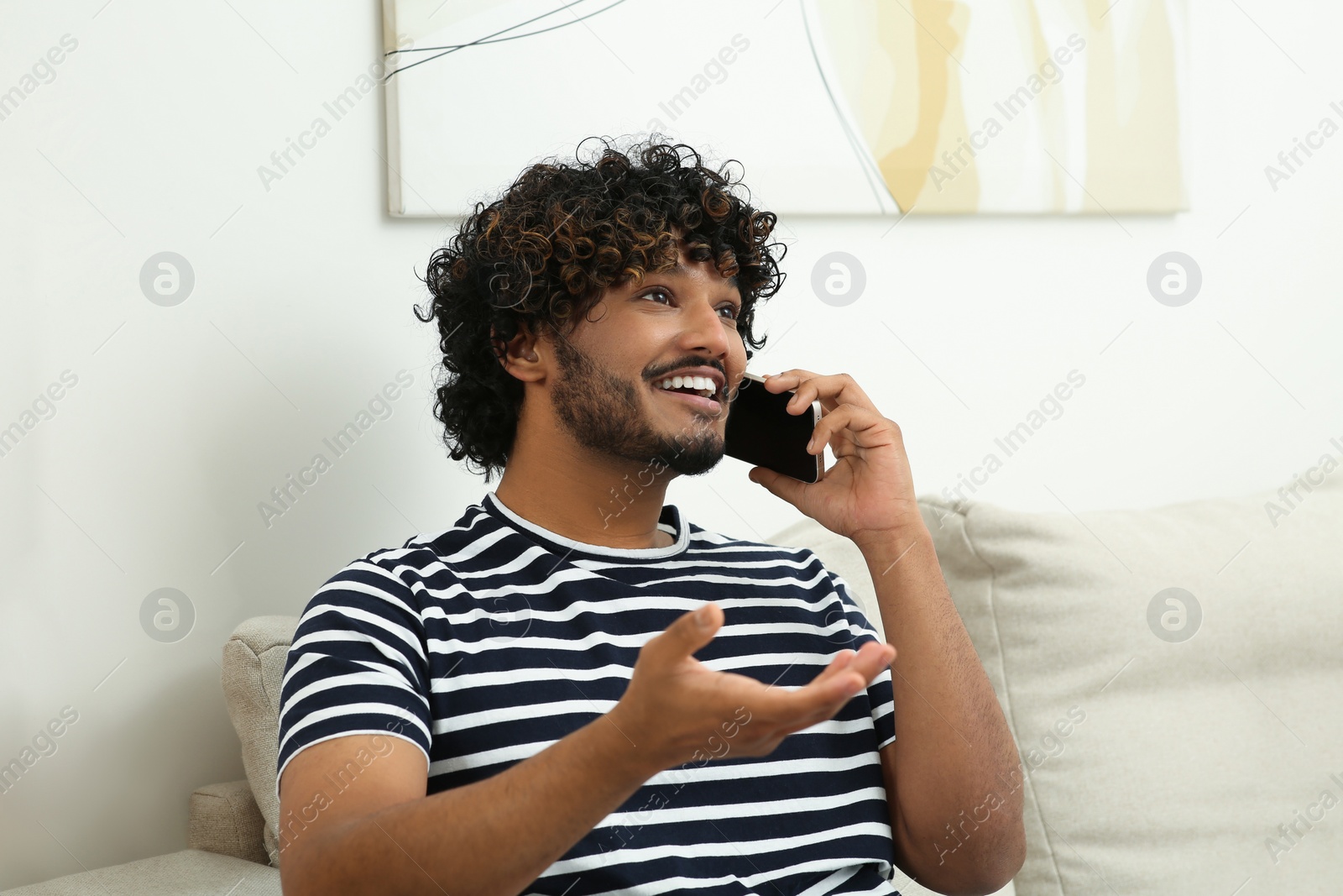 Photo of Handsome smiling man taking over smartphone indoors