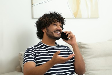 Photo of Handsome smiling man taking over smartphone indoors