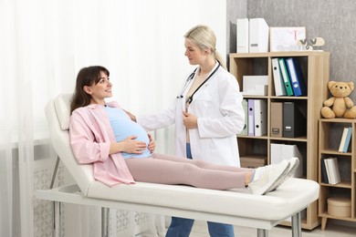 Happy pregnant woman having doctor appointment in hospital