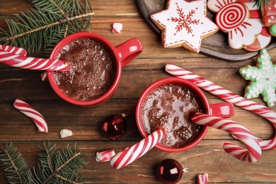 Flat lay composition with cups of hot chocolate and Christmas candy canes on wooden table