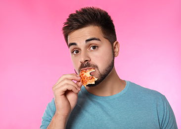 Photo of Emotional man eating pizza on pink background