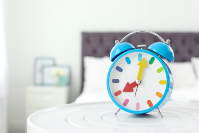 Photo of Colorful alarm clock on table in bedroom. Time to wake up