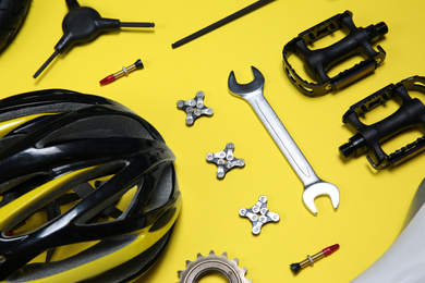 Set of different bicycle tools and parts on yellow background, above view