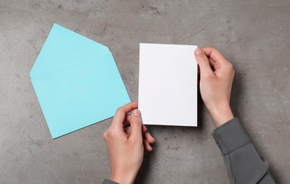 Photo of Woman with blank sheet of paper at grey textured table, top view. Space for text