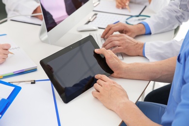 Photo of Male doctor working with tablet at table. Cardiology conference