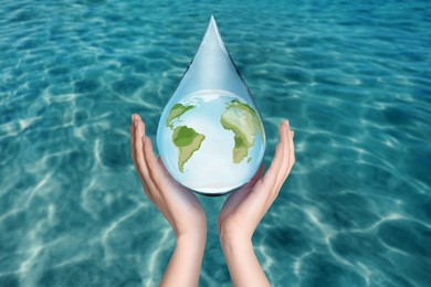 Image of Woman holding icon of Earth in drop on blue background, closeup. Water save concept