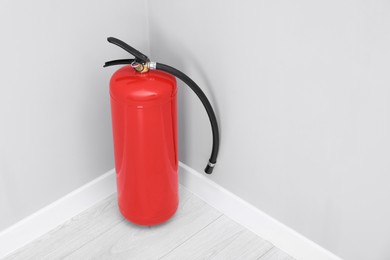 Fire extinguisher on floor indoors, space for text