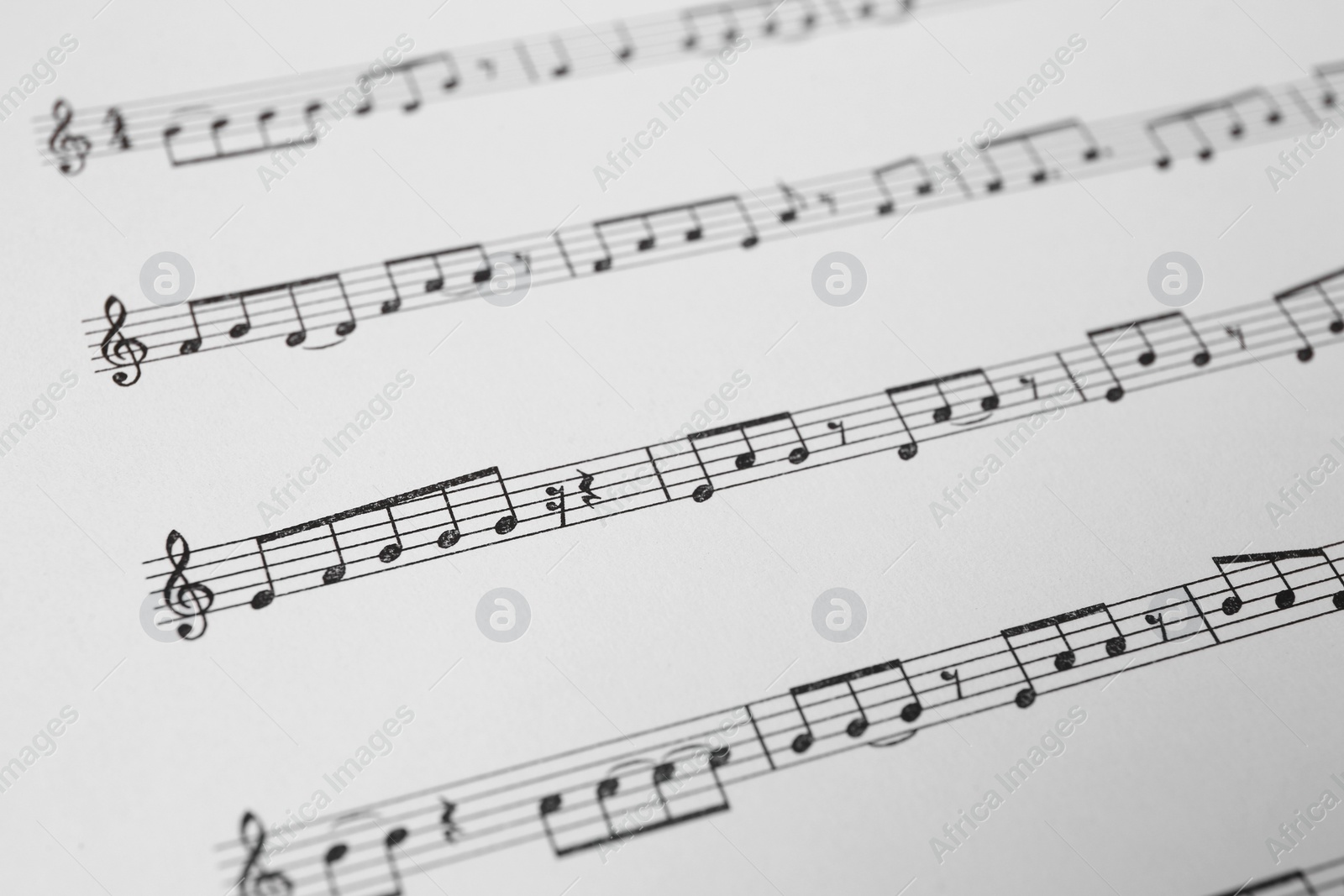 Photo of Sheet of paper with music notes as background, closeup