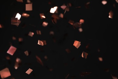 Photo of Shiny pink confetti falling down on black background