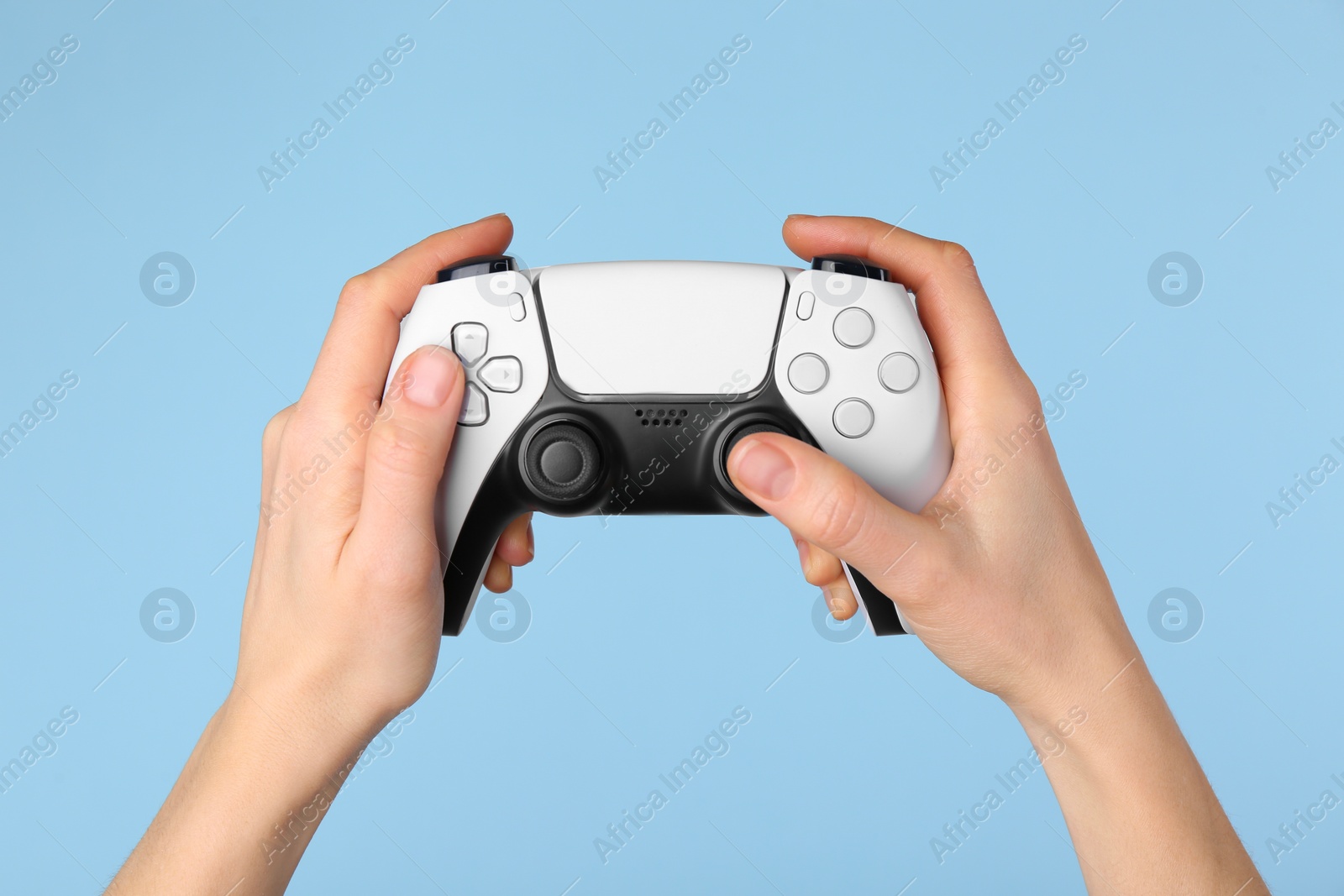 Photo of Woman using game controller on light blue background, closeup