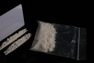 Photo of Drug addiction. Plastic bag with cocaine and blank card on black table