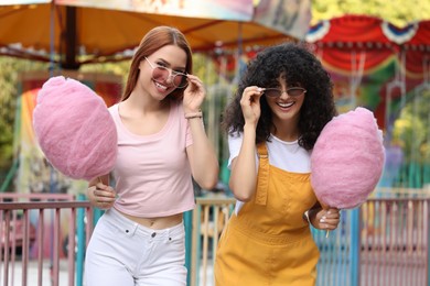 Happy friends with cotton candies at funfair