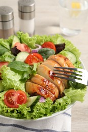 Photo of Eating delicious salad with chicken and vegetables at table, closeup